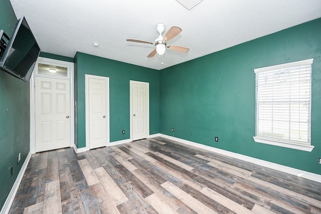 unfurnished bedroom with ceiling fan and dark hardwood / wood-style floors