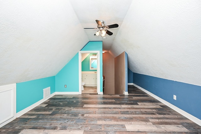 additional living space featuring a textured ceiling, dark hardwood / wood-style flooring, vaulted ceiling, and ceiling fan