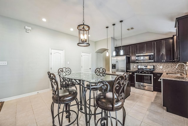 kitchen with sink, light tile patterned floors, pendant lighting, a kitchen island, and appliances with stainless steel finishes