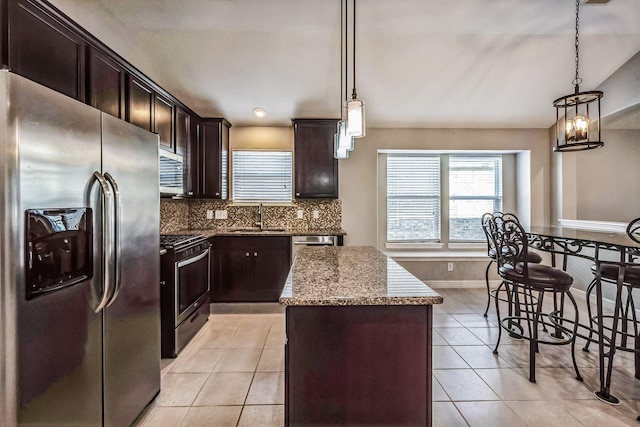 kitchen featuring appliances with stainless steel finishes, a center island, decorative light fixtures, and sink