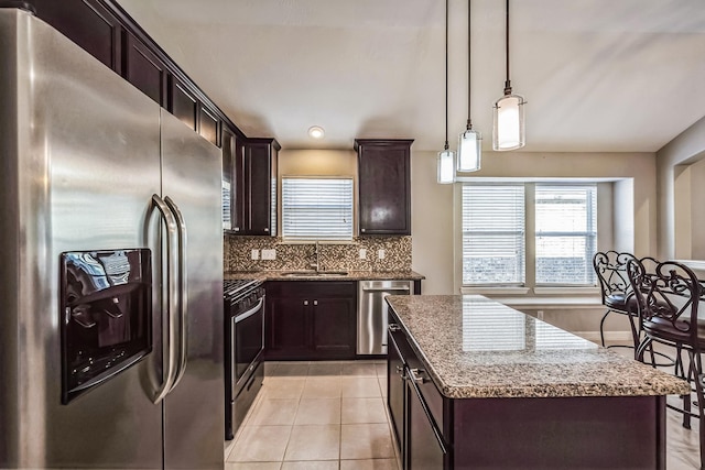 kitchen with a center island, sink, hanging light fixtures, decorative backsplash, and stainless steel appliances