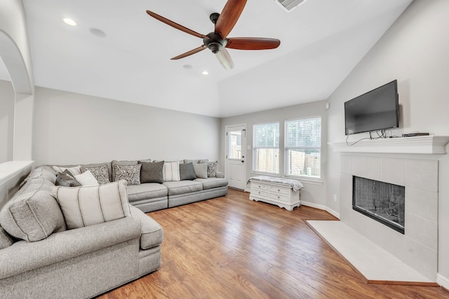 living room featuring ceiling fan, a fireplace, lofted ceiling, and light wood-type flooring