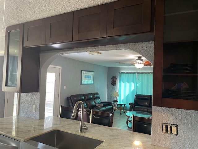 kitchen featuring light stone countertops, stainless steel dishwasher, ceiling fan, and sink