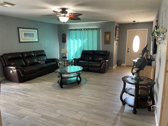 living room with ceiling fan, light hardwood / wood-style floors, and a textured ceiling