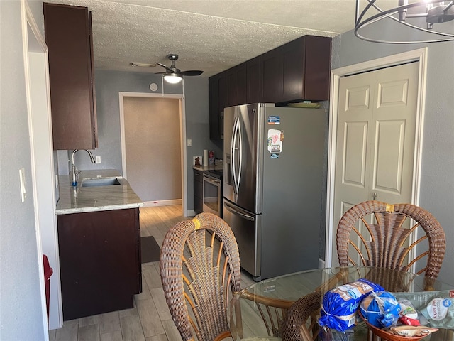 kitchen with dark brown cabinets, a textured ceiling, ceiling fan, sink, and stainless steel fridge with ice dispenser