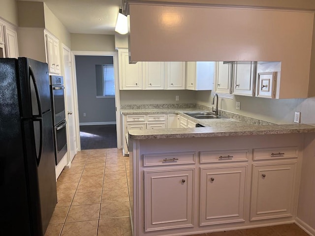 kitchen with black refrigerator, kitchen peninsula, sink, light tile patterned floors, and white cabinetry