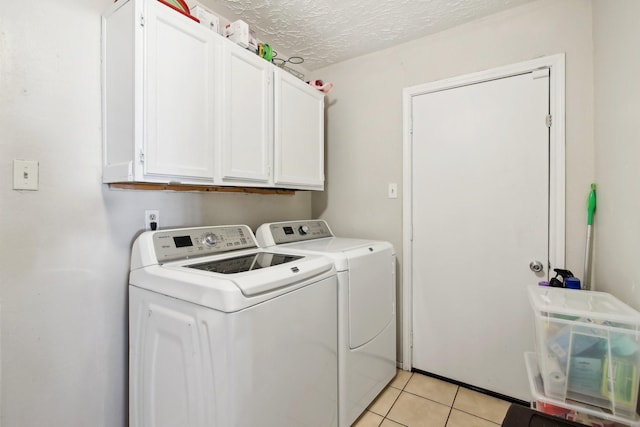 laundry room with cabinets, light tile patterned floors, a textured ceiling, and separate washer and dryer