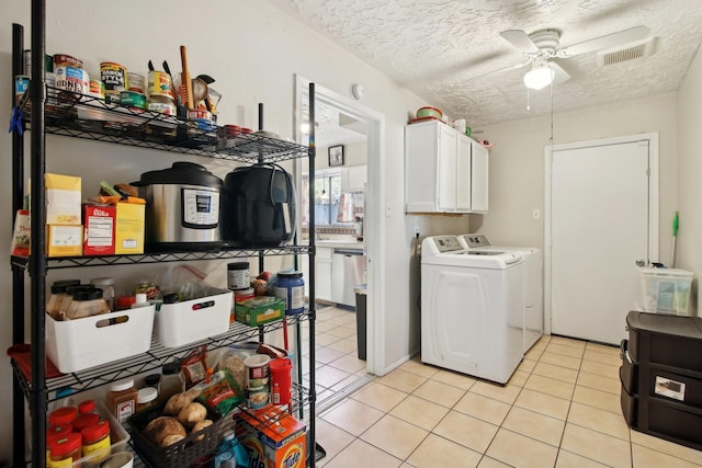 clothes washing area featuring cabinets, ceiling fan, independent washer and dryer, a textured ceiling, and light tile patterned flooring