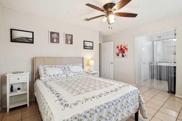 bedroom featuring a textured ceiling, ceiling fan, and light tile patterned flooring