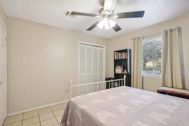 tiled bedroom featuring ceiling fan, a textured ceiling, and a closet