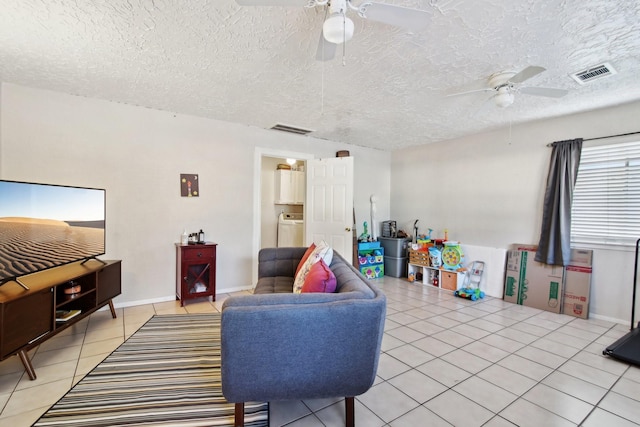 tiled living room with a textured ceiling, washer / clothes dryer, and ceiling fan