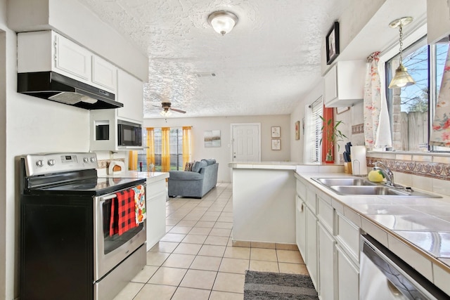 kitchen featuring appliances with stainless steel finishes, sink, white cabinetry, plenty of natural light, and light tile patterned flooring