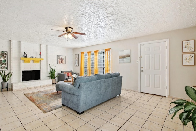 tiled living room featuring a textured ceiling, a brick fireplace, and ceiling fan