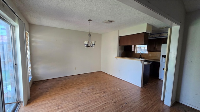 kitchen featuring hardwood / wood-style floors, backsplash, sink, a notable chandelier, and dark brown cabinetry