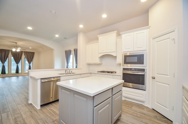 kitchen with white cabinets, stainless steel appliances, a kitchen island, and sink