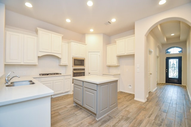 kitchen featuring white cabinets, a center island, black microwave, and sink