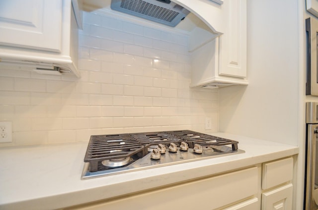 kitchen featuring white cabinets, stainless steel gas stovetop, extractor fan, and tasteful backsplash