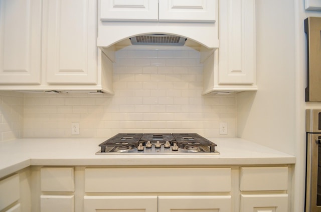 kitchen with decorative backsplash, oven, and stainless steel gas cooktop