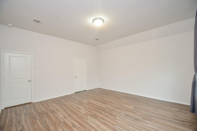 unfurnished room with vaulted ceiling and light hardwood / wood-style flooring