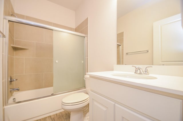 full bathroom with shower / bath combination with glass door, hardwood / wood-style floors, vanity, and toilet