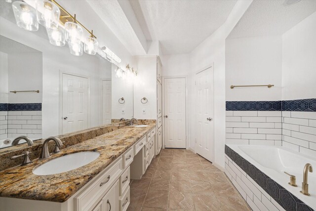 bathroom featuring vanity, tile patterned flooring, a relaxing tiled tub, and a textured ceiling