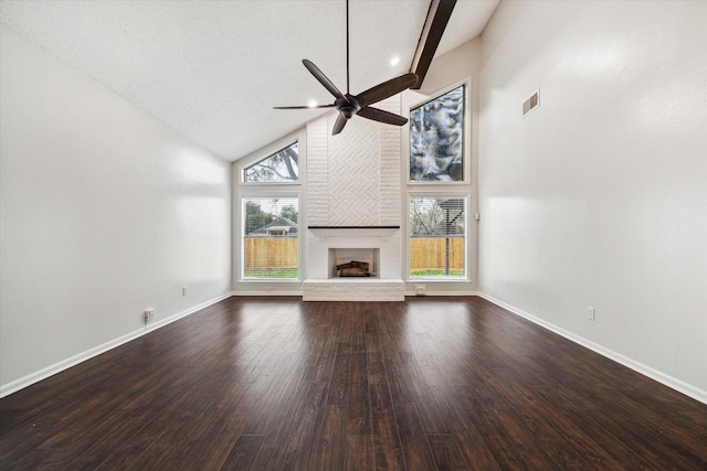 unfurnished living room with ceiling fan, dark wood-type flooring, a brick fireplace, high vaulted ceiling, and a textured ceiling