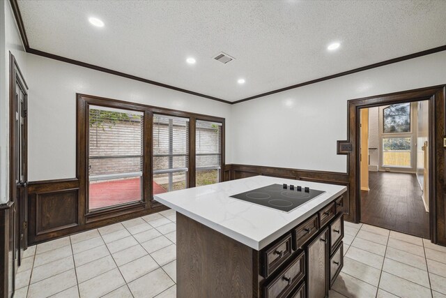 kitchen with a textured ceiling, electric cooktop, a kitchen island, and light tile patterned floors