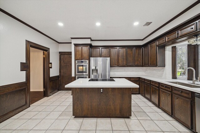 kitchen with appliances with stainless steel finishes, a center island, dark brown cabinets, and sink