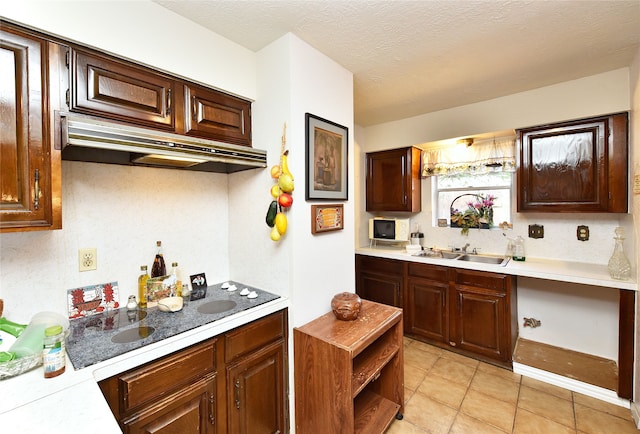 kitchen with a textured ceiling, light tile patterned flooring, and sink