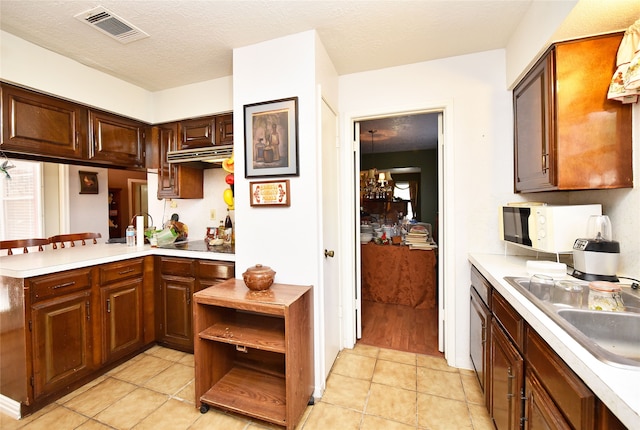 kitchen with kitchen peninsula, black electric cooktop, sink, a chandelier, and light tile patterned flooring