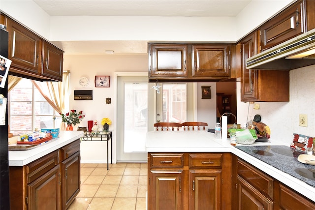 kitchen with light tile patterned flooring, kitchen peninsula, and premium range hood