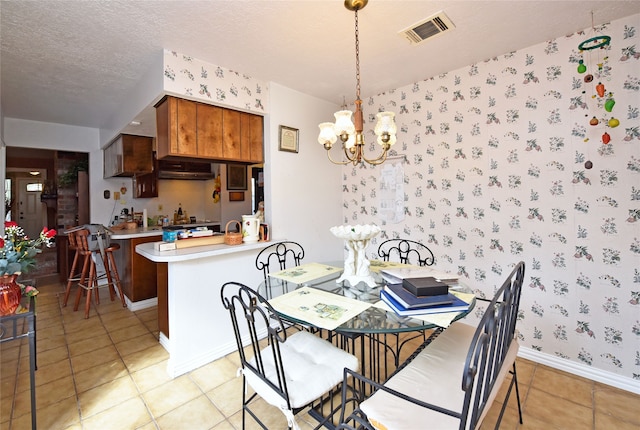 tiled dining space featuring a textured ceiling and an inviting chandelier