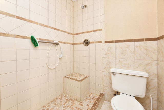bathroom featuring a tile shower, toilet, and tile walls