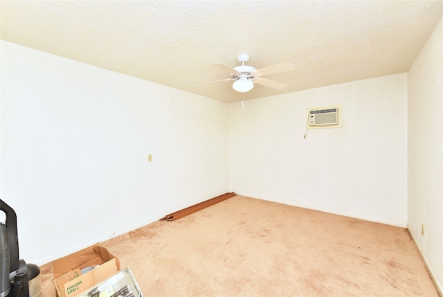 empty room with a textured ceiling, light carpet, ceiling fan, and a wall mounted air conditioner