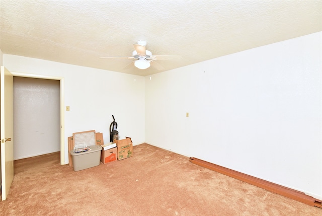 unfurnished room with a textured ceiling, ceiling fan, and light carpet