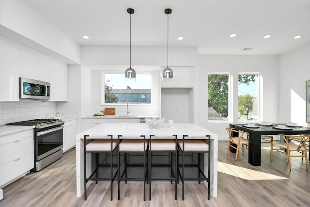 kitchen with a center island, sink, stainless steel appliances, decorative backsplash, and white cabinets