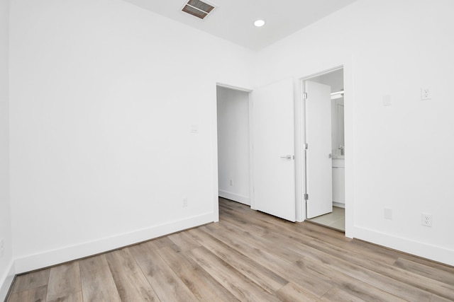 unfurnished bedroom featuring connected bathroom and light hardwood / wood-style floors