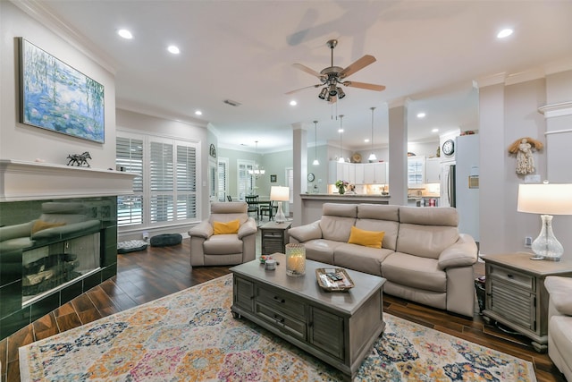 living room featuring a tile fireplace, crown molding, ceiling fan, and dark wood-type flooring