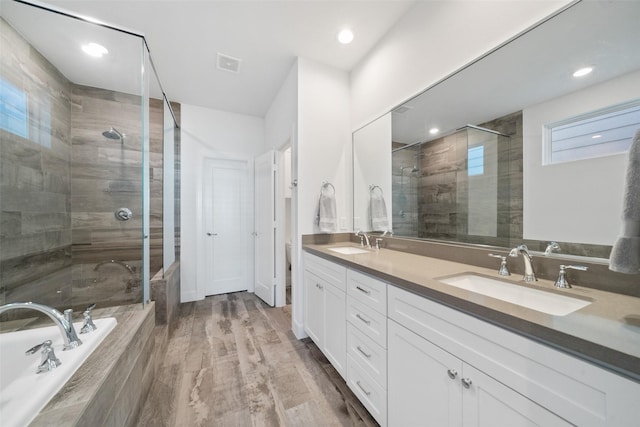 bathroom featuring hardwood / wood-style flooring, vanity, and plus walk in shower