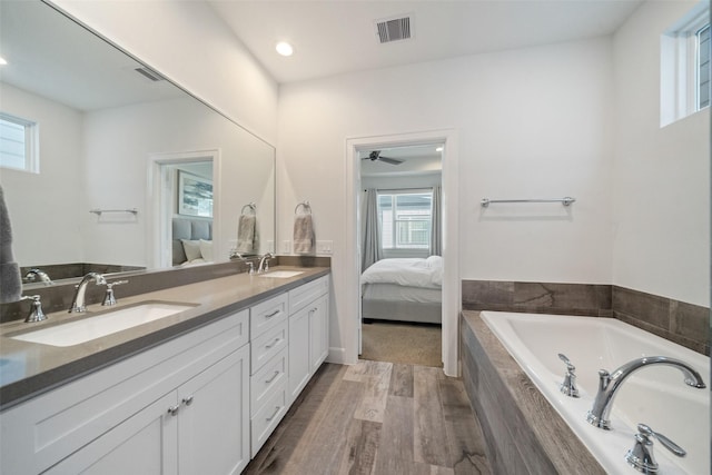 bathroom with vanity, ceiling fan, wood-type flooring, and tiled tub