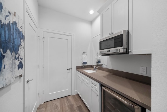 kitchen featuring hardwood / wood-style flooring, white cabinetry, sink, and wine cooler