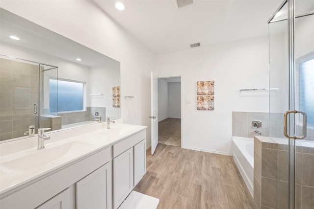 bathroom featuring hardwood / wood-style flooring, vanity, and plus walk in shower