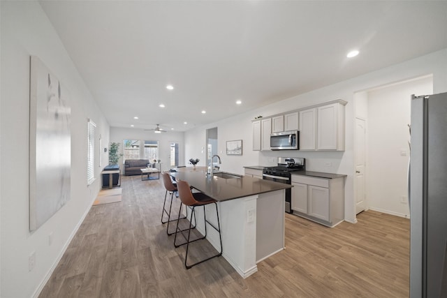 kitchen with ceiling fan, appliances with stainless steel finishes, a kitchen island with sink, a kitchen breakfast bar, and sink