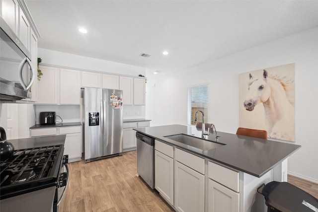 kitchen with a center island with sink, a breakfast bar, sink, white cabinetry, and appliances with stainless steel finishes