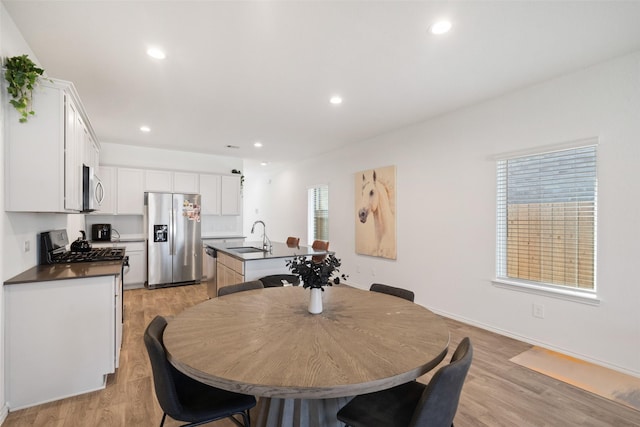 dining area featuring a healthy amount of sunlight, light hardwood / wood-style flooring, and sink