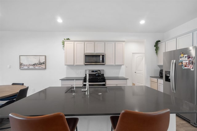 kitchen with white cabinetry, light wood-type flooring, stainless steel appliances, and a center island with sink