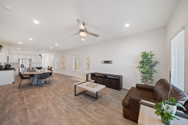 living room featuring light hardwood / wood-style floors, ceiling fan, and a healthy amount of sunlight