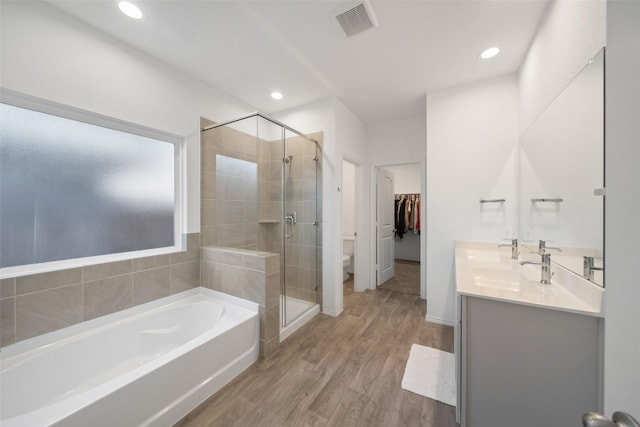 full bathroom with hardwood / wood-style floors, toilet, vanity, and shower with separate bathtub