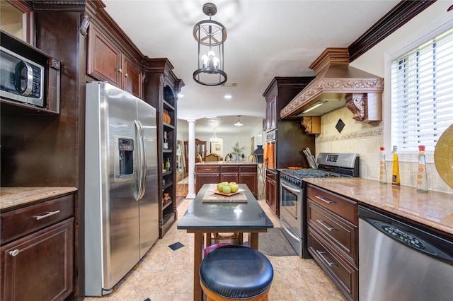 kitchen featuring decorative backsplash, appliances with stainless steel finishes, decorative columns, premium range hood, and decorative light fixtures