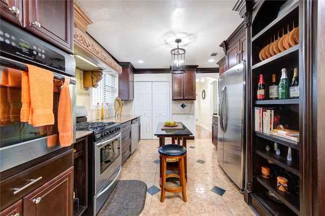 kitchen with pendant lighting, a kitchen breakfast bar, ornamental molding, appliances with stainless steel finishes, and tasteful backsplash